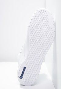 Baskets Reebok blanches avec une semelle en caoutchouc texturée présentant un motif en chevrons et un détail de logo. Tige en cuir lisse au design minimaliste.