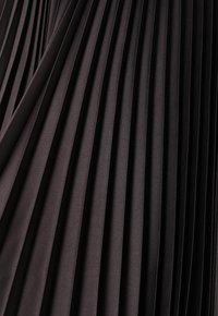 Tissu noir plissé présentant des plis verticaux, une texture lisse et une finition légèrement brillante, mettant en valeur un design uniforme et structuré.