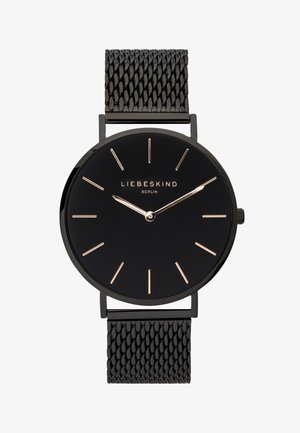 Rund sort ur med et sleek sort meshrem. Uret har guld timemarkører og visere, med "LIEBESKIND BERLIN" indgraveret på urskiven.