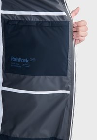 Jakna otporna na vodu s sivom vanjštinom, bijelim akcentima i velikim unutarnjim džepom s logotipom "RainPack". Glatka tekstura.