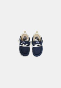 Scarpe slip-on in denim blu con lacci bianchi, suola in gomma crema e interno imbottito. Presentano un logo sulla linguetta e sul tallone.