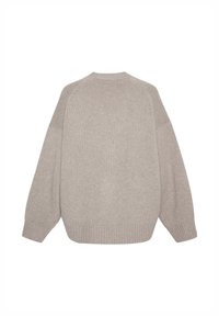Pull en maille beige à coupe décontractée, manches raglan et poignets en côtes. La texture est douce avec un motif subtil.