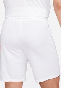 Shorts de sport blancs en tissu léger, dotés d'une ceinture élastique et d'une texture lisse. Pas de motifs ou de designs visibles.