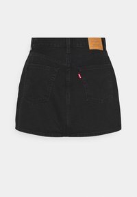 Mini-jupe en jean noir avec deux poches arrière, passants pour ceinture et un patch en cuir de la marque Levi’s à la taille.