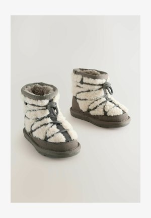 Bottes en polaire grises et blanches avec un col rembourré, un design à lacets, une semelle en caoutchouc et un tissu texturé pour la chaleur et le confort.