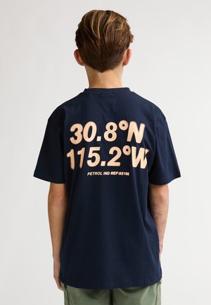 T-shirt en coton bleu marine avec un grand imprimé beige au dos affichant des coordonnées géographiques et "PETROL IND REF-92106." Manches courtes.