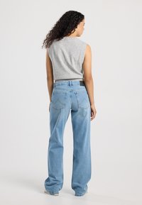 Gray sleeveless top paired with high-waisted light blue wide-leg jeans, featuring back pockets and a stitched design on the denim.
