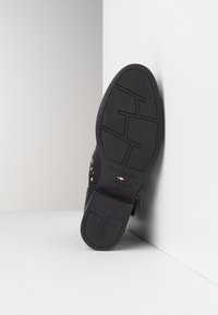 Zwarte leren schoenzool met gestructureerd rubber, met verhoogde patronen en kleine metalen studs langs de randen. Gemarkeerd met "NeroGiardini, Made in Italy, 37."