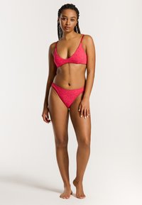 Rosa Bikini-Set mit einem Triangel-Oberteil mit dünnen Trägern und einem strukturierten, verrückten Muster, kombiniert mit passenden, tief sitzenden Unterteilen.
