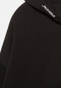 Fekete kapucnis pulóver, amely puha, texturált anyagból készült, laza szabással. A kapucni szélén fehér „STUDIO” felirat hímzett.