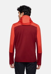 Rot und orange Kapuzenpullover mit strukturierter Körperpartie und glatter Kapuze. Verfügt über lange Ärmel, kontrastierende Schulterpaneele und ein tailliertes Design.