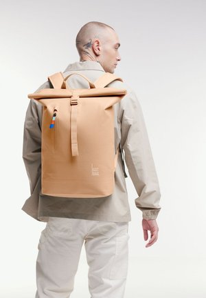Zaino roll-top in morbido materiale pesca con tasca frontale a zip e accenti a contrasto in blu, bianco e arancione. Branding nella sezione inferiore.