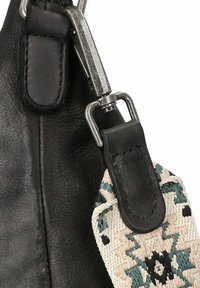 Correa de bolsa de cuero negro con herrajes metálicos plateados, que presenta una banda textil decorativa trenzada en patrones geométricos en beige y verde azulado.