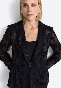 Must valoredu sandaal mustriga lillekõrgem ahvikarva tikand ja sädelus. Omab nurgaklappi ja ühte nööbi sulgemist, kohandatud sobivus.