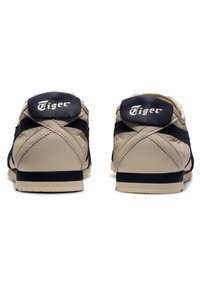 Beżowe i granatowe sneakersy o gładkim skórzanym wykończeniu, z wyściełanym zapiętkiem, zaokrąglonym noskiem i wyraźnym logo "Tiger" na pięcie.