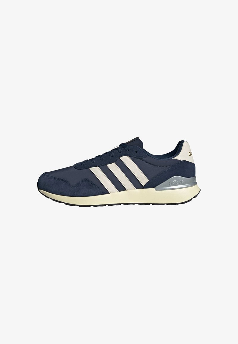 Baskets Adidas bleu marine avec des bandes blanches, semelle beige et accent argenté au talon, vues de côté extérieur sur fond blanc.