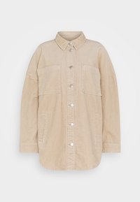 Beige kordflöjeljacka med knäppning fram, krage, två stora bröstfickor och en lös passform. Har en ribbad textur och silverdetaljer.