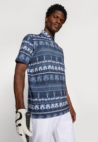 Polo a maniche corte di colore blu scuro con motivi bianchi di palme e geometrici. Realizzato in tessuto leggero con colletto a punta.