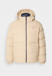 Veste matelassée beige avec fermeture éclair frontale, poignets élastiques, capuche avec cordons ajustables et petit logo Tommy Hilfiger sur la poitrine.