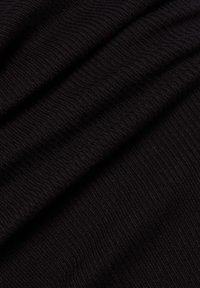 Zwart textiel met een ribbelpatroon, dat een zacht, iets rekbaar materiaal toont. Lagen overlappen elkaar, waardoor diepte in kleur en textuur zichtbaar wordt.