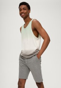 Lichtgroene naar grijze gradient katoenen tanktop gecombineerd met grijze katoenen shorts. De tank heeft brede armsgaten en een relaxte pasvorm. Soepele textuur.
