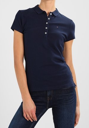 Polo azul marino de tela suave, con cuello clásico, mangas cortas y una tapeta con botones blancos contrastantes.