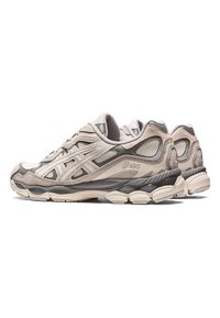 Paire de chaussures de course beige et grises Asics avec des panneaux en mesh et en daim, semelles épaisses et rembourrées, et lacets vues de côté.