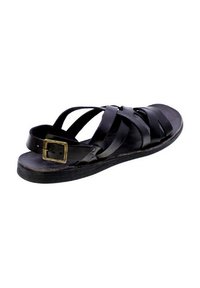 Sandal in pelle nera con cinturini incrociati, fibbia regolabile, suola piatta e plantare testurizzato. Design minimalista, aspetto casual.