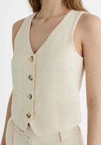 Beige linnen vest met een diepe V-hals, vijf knopen aan de voorzijde en twee voorzakken, gemaakt van een licht gestructureerde stof.