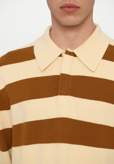 Ribaga polo särk, millel on beeži ja pruuni horisontaalsetes triipudes, krae ning tekstureeritud kudum. Klassikaline nööbiplokiga detail.