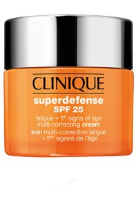 Clinique Superdefense SPF 25 kräm i en genomskinlig orange burk med ett skinande silverlock. Har svart text som anger anti-aging fördelar.