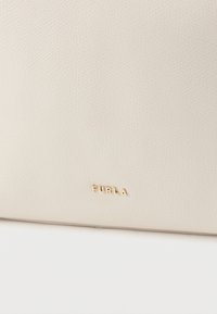 Kreemjas nahast kott tekstuurse pinnaga ja kuldse reljeefse logoga. Omab minimalistlikku disaini ja puhtaid jooni, sobib mitmesugusteks sündmusteks.