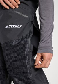 Crne Terrex hlače imaju teksturirani dizajn na donjem dijelu, bočni zip džep i istaknut Terrex logo na gornjem dijelu bedra.