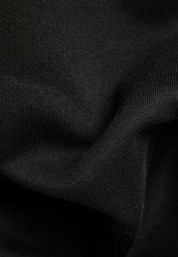Tela negra con una superficie suave y ligeramente texturizada, que muestra una calidad blanda y elástica, y un patrón de tejido uniforme.