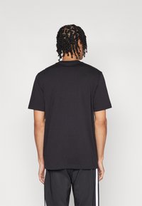 Zwarte katoenen t-shirt met korte mouwen en een ronde hals, met een eenvoudig ontwerp en een gladde textuur, gezien van achteren.