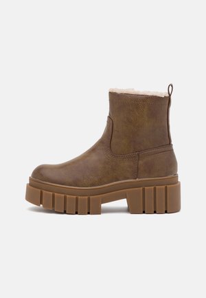 Brown ankle boot with textured synthetic material, soft faux fur lining, rounded toe, and chunky ridged sole for stability.
