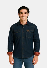 Dunkelblaues Jeanshemd mit spitzem Kragen, zwei Brusttaschen und geometrisch gemusterten Manschetten in rötlich-braun. Verfügt über Messingknöpfe und kontrastierende Nähte.