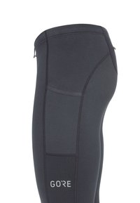 Leggings de sport noirs au fit ajusté, présentant des détails de couture et une petite poche zippée sur la taille. Logo de la marque affiché.