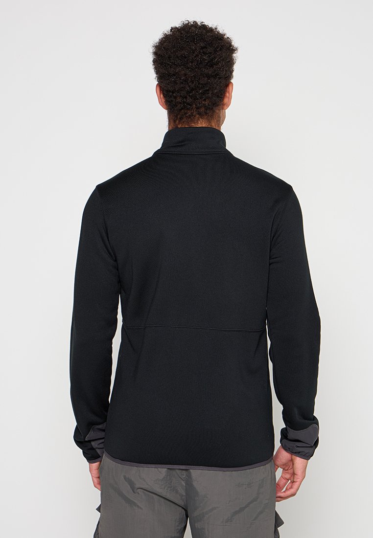 Veste en polaire noire à manches longues avec un col haut, texture lisse et accents gris contrastants sur les poignets et l'ourlet.