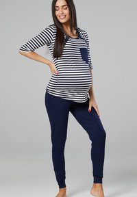 Maternity outfit featuring a navy and white striped top with a pocket and buttons, paired with solid navy leggings. Soft, stretchy fabric.