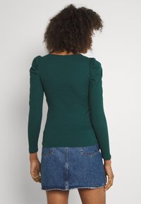 Grön randig långärmad topp med puffärmar, matchad med en blå denimkjol med fransad fåll och bakfickor.