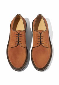 Scarpe in camoscio beige con punta arrotondata, design con cinque occhielli per allacciatura, cuciture a contrasto e suola marrone strutturata.