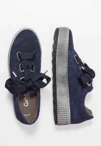 Zapatillas de ante en color navy con cordones grandes en navy, ojales plateados, una suela texturizada en negro y acentos decorativos en gris a lo largo del borde de la suela.