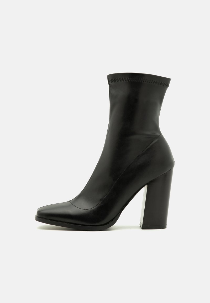 Bottines en cuir noir avec un ajustement serré, bout pointu et un talon haut épais. Présente une surface lisse et des détails de couture subtils.