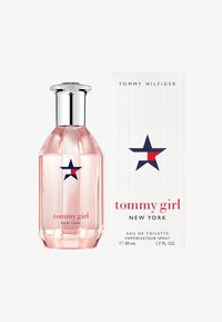 Bottiglia di profumo in vetro rosa con tappo argentato, decorata con una stella blu navy e dettagli rossi. Accompagnata da una scatola bianca con testo in rilievo.