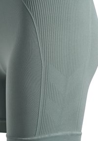 Legginsy wysokie w talii w jasnym zielonym kolorze, z prążkowaną teksturą i wzorami w jodełkę, z gładkim pasem w talii i dopasowanym krojem.