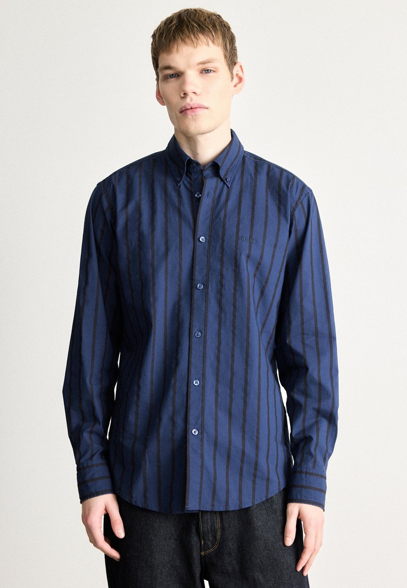 Siniste triipudega nööbitav särk kraega; õhukesed vertikaalsed triibud, ümaralõikega alumine serv ja sinised nööbid; rinnal peen brändilogo.