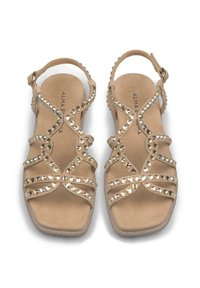 Sandali beige con cintini in suede, dotati di strass brillanti lungo i cintini e una suola testurizzata e luccicante. Design a punta quadrata.