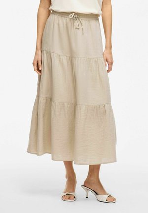Falda en capas de color beis claro, fabricada en tela suave, con cinturilla elástica y cordón para un ajuste regulable y una silueta fluida.