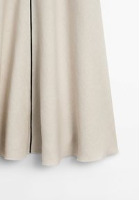 Jupe en tissu beige avec une légère évasée et une seule couture noire verticale au centre devant.